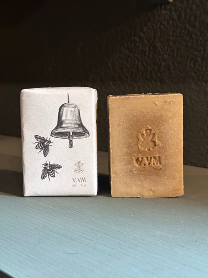 Two soap bars with branding on a dark surface